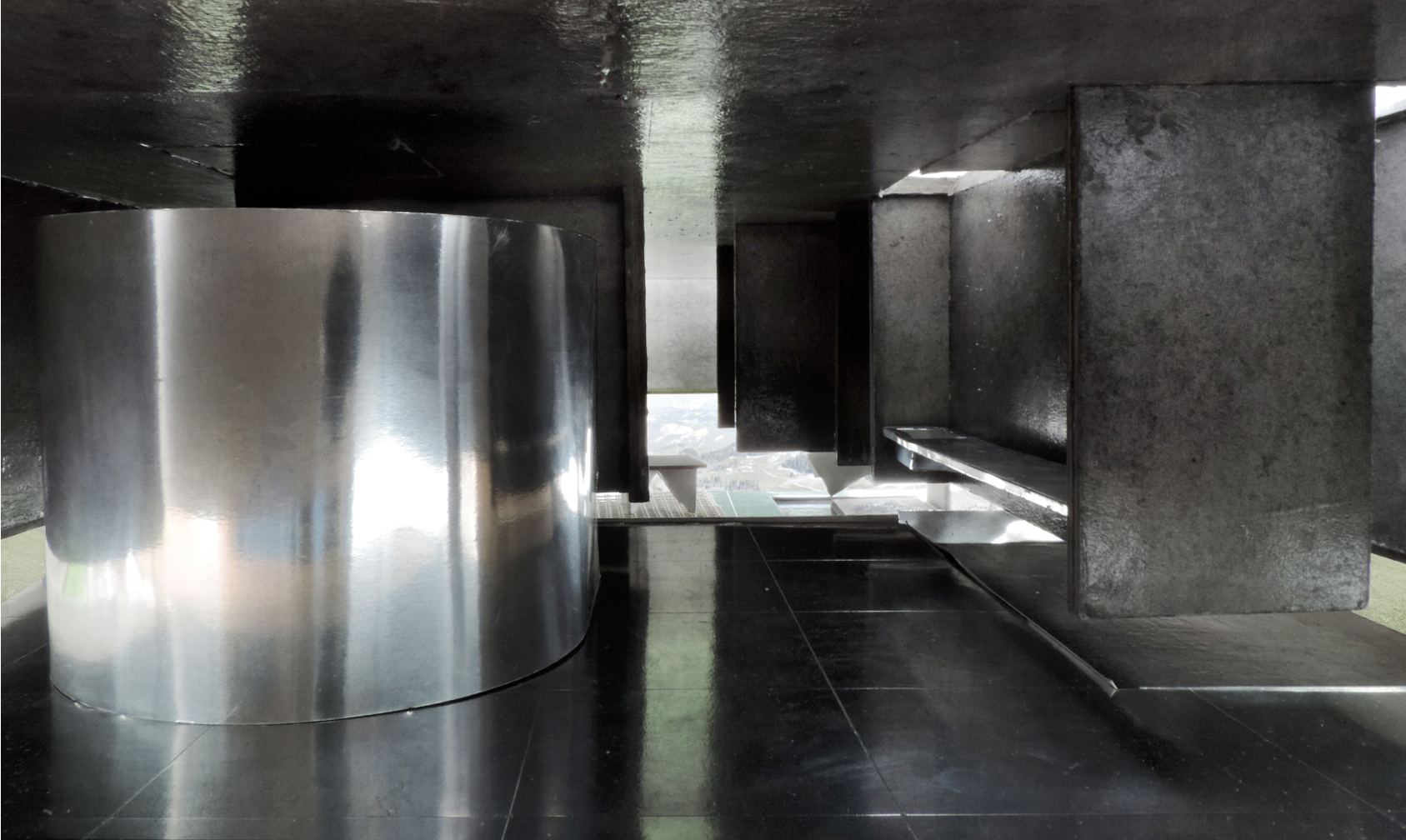 Model photograph: a polished metal cylinder in a dark interior